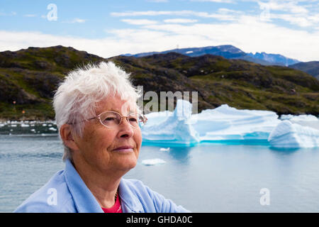Senior retired OAP lady tourist passenger on a fjord cruise ship retirement holiday with icebergs from Tunulliarfik fjord in summer. Narsaq, Greenland Stock Photo