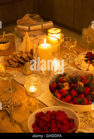 Food and decorations on candlelight Christmas table Stock Photo