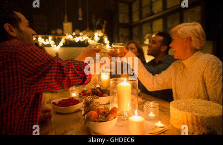 Friends toasting champagne glasses at candlelight Christmas dinner party Stock Photo