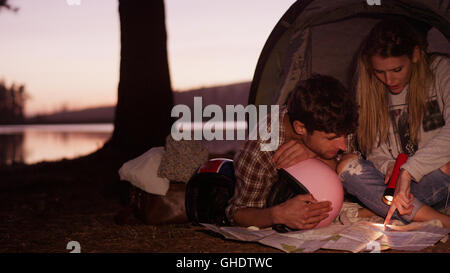 Young couple looking at maps in camping tent Stock Photo