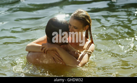 Affectionate couple hugging and swimming in sunny lake Stock Photo