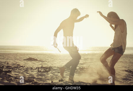 Playful couple dancing on sunny beach at sunset Stock Photo