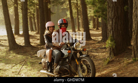 Young couple riding motorcycle in woods Stock Photo