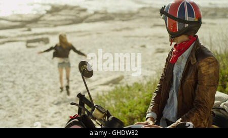 Young man on motorcycle watching woman run onto beach
