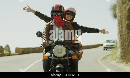 Exuberant young woman riding motorcycle on sunny road Stock Photo