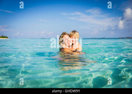 Enthusiastic mother hugging son in tropical ocean Stock Photo