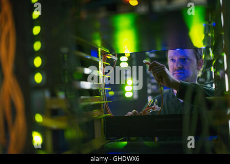 Server room technician with cable at panel Stock Photo