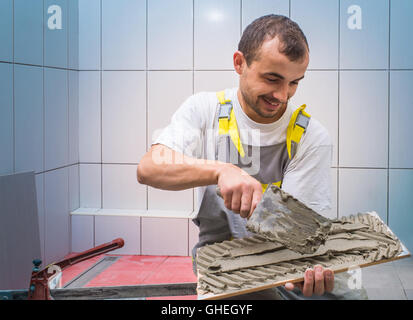 industrial tiler builder worker installing floor tile Stock Photo