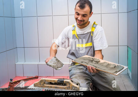 industrial tiler builder worker installing floor tile Stock Photo