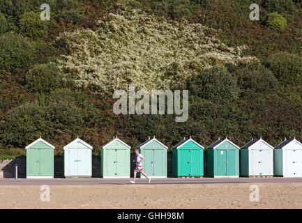 Bournemouth, Dorset, UK. 28 September 2016. Runner running past shades of green beach huts along promenade of various shades of green with green foliage background on a glorious warm sunny day. Credit:  Carolyn Jenkins/Alamy Live News Stock Photo