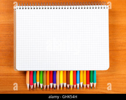 notebook and a set of colored pencils on wooden background Stock Photo