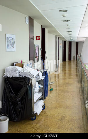 Trolley full of clean linen and room supplies in hotel corridor Stock Photo