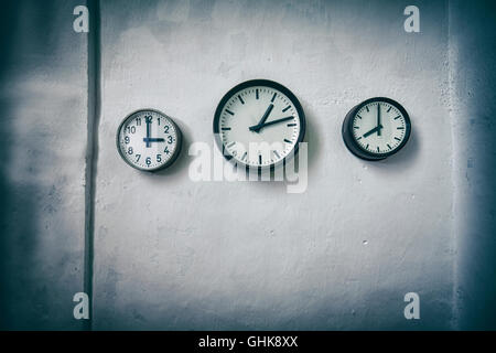 Vintage toned clocks on a grunge wall, time passing concept, space for text with vignette effect. Stock Photo