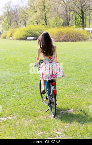 Young woman riding bike in spring park Stock Photo