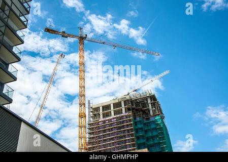Cranes on building site of new apartment block with sky and jet stream Stock Photo