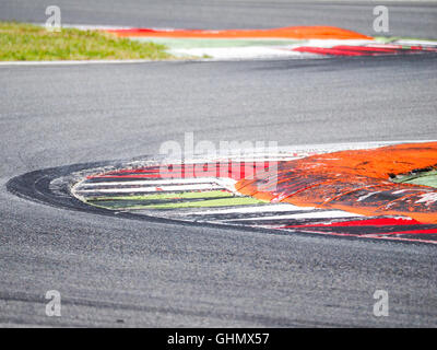 Close view of circuit corner curb with tyre's signs on asphalt, perfect for motor sport concepts and background. Stock Photo