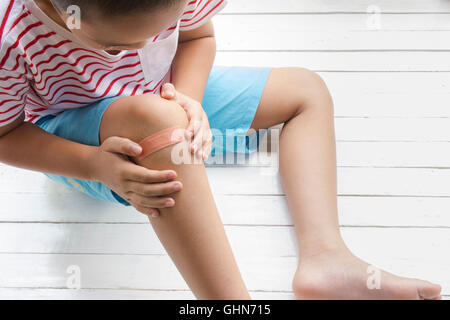 Children wound or The boy had an accident sitting on wooden white background.Top view and Stock Photo