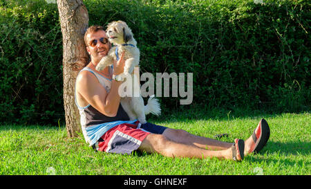 man and a dog hugging in a green park Stock Photo