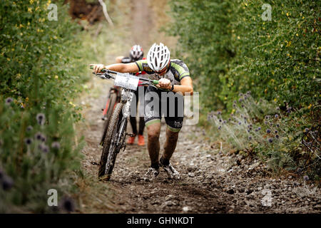 two men mountainbikers climb mountain on foot with their bicycle during Regional competitions on cross-country bike Stock Photo