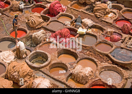 Workers in vats dyeing animal hide to be made into slippers (babouche) at famous tanneries of Fes, Morocco. Stock Photo