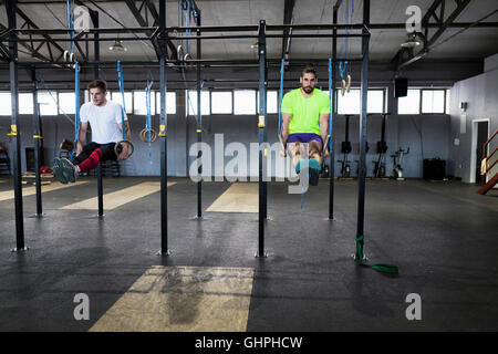 Two men doing gym exercise on rings in gym Stock Photo