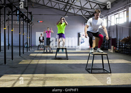 Athletes doing box jumps in gym Stock Photo