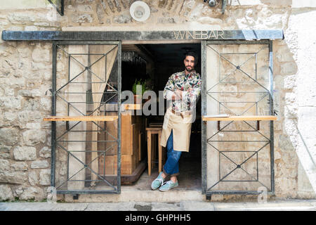 Male owner of wine bar leaning against entrance door Stock Photo