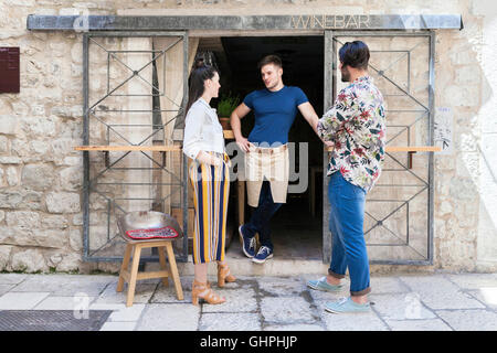 Owner of wine bar talking to friends outside Stock Photo