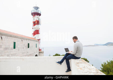 Young woman using digital tablet near lighthouse Stock Photo