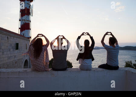 Young people making heart shapes with hands at the seaside Stock Photo