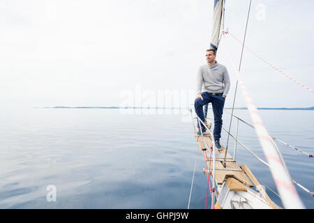 Man stands on bow of yacht day looking at sea Stock Photo