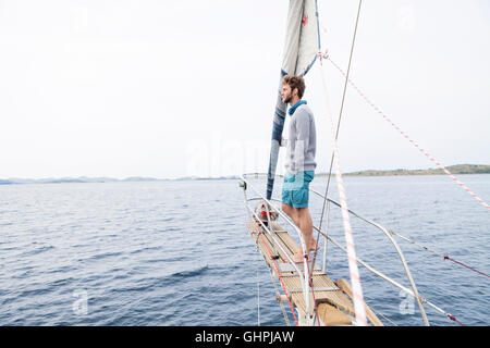 Young man stands on bow of yacht day dreaming Stock Photo