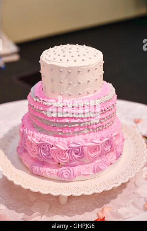 beautiful pink three-tiered wedding cake on table Stock Photo