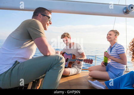 Young man playing guitar on sailboat Stock Photo