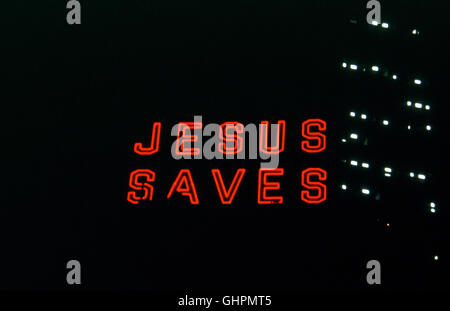 'Jesus Saves' neon sign in lit up at night in urban setting Stock Photo