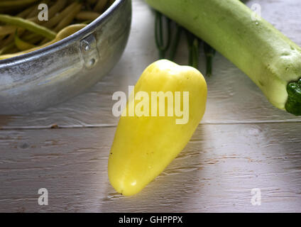 French bean in a colander, zucchini, bell pepper and dill on a white painted wooden surface Stock Photo