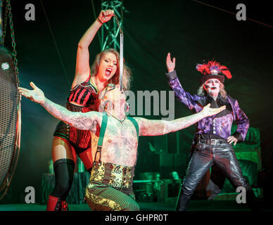 Circus of Horrors cast: Sword swallower, assistant and ring master in mid performance. Stock Photo