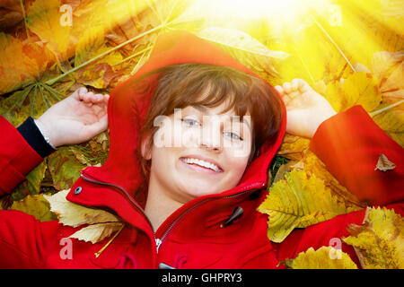 Happy girl lying in autumn leaves Stock Photo