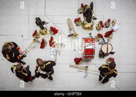 Viewed from above a military brass band leave their instruments on the floor while they engage in conversation Stock Photo