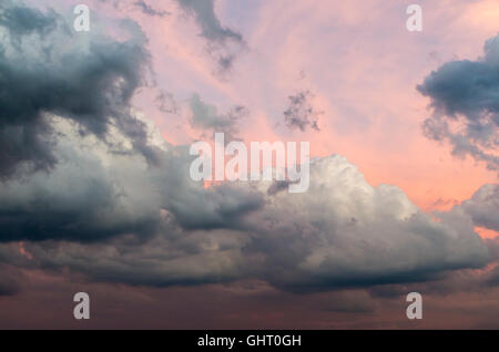Grey cumulus congestus and cumulonimbus storm clouds after a thunderstorm at sunset glowing red Stock Photo
