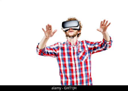 Young curly-haired man in plaid shirt using a VR headset and experiencing virtual reality isolated on white background Stock Photo