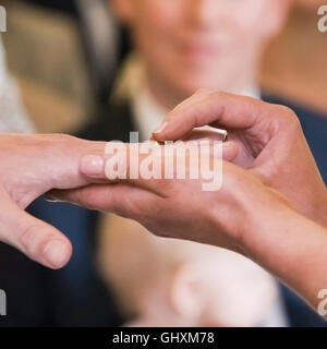 Square close up of a bride placing the ring on the groom's hand during a civil wedding ceremony. Stock Photo