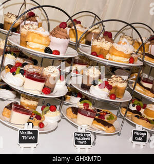 Square close up of cakes and pastries arranged on cake stands at a tearoom. Stock Photo