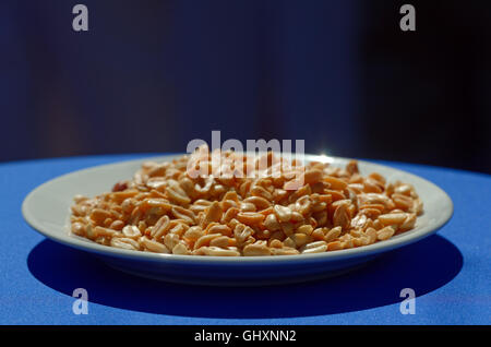 Plate of peanuts on a blue tablecloth Stock Photo