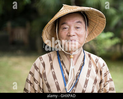 Elderly Okinawan man in his 70's wearing traditional bashofu style kimono and straw hat. Okinawa is a longevity blue zone. Stock Photo