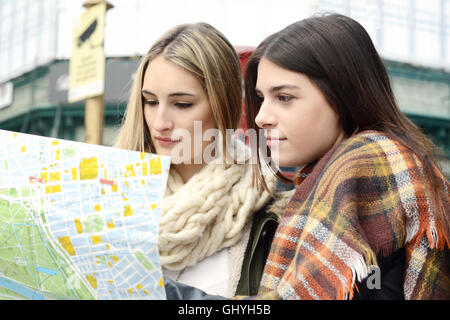 Portrait of two young tourists looking at a map. Tourism concept. Outdoors. Stock Photo