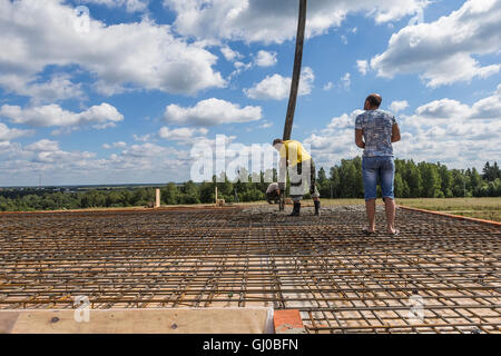 Workers poured concrete using a concrete pump with a vibrator. Stock Photo