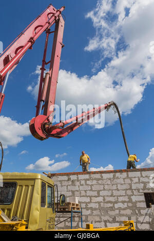 Workers poured concrete using a concrete pump with a vibrator. Stock Photo