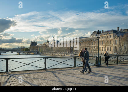 a couple kissing on the Pont des Arts over the River Seine with the Palais du Louvre, Paris, France Stock Photo