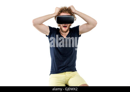 Young curly-haired man using a VR headset and experiencing virtual reality isolated on white background Stock Photo
